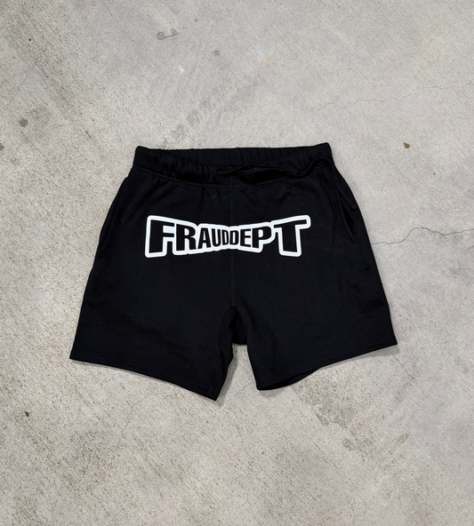 Black shorts with 'FRAUDEPT' printed on them on a concrete floor.